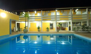 A hotel with a swimming pool, multiple balconies, and potted plants. - Rede Andrade Porto Seguro Navegantes (Porto Seguro)