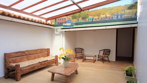 A covered patio with a wooden bench, two chairs, a small table, and a potted plant. - Rede Andrade Porto Seguro Navegantes (Porto Seguro)