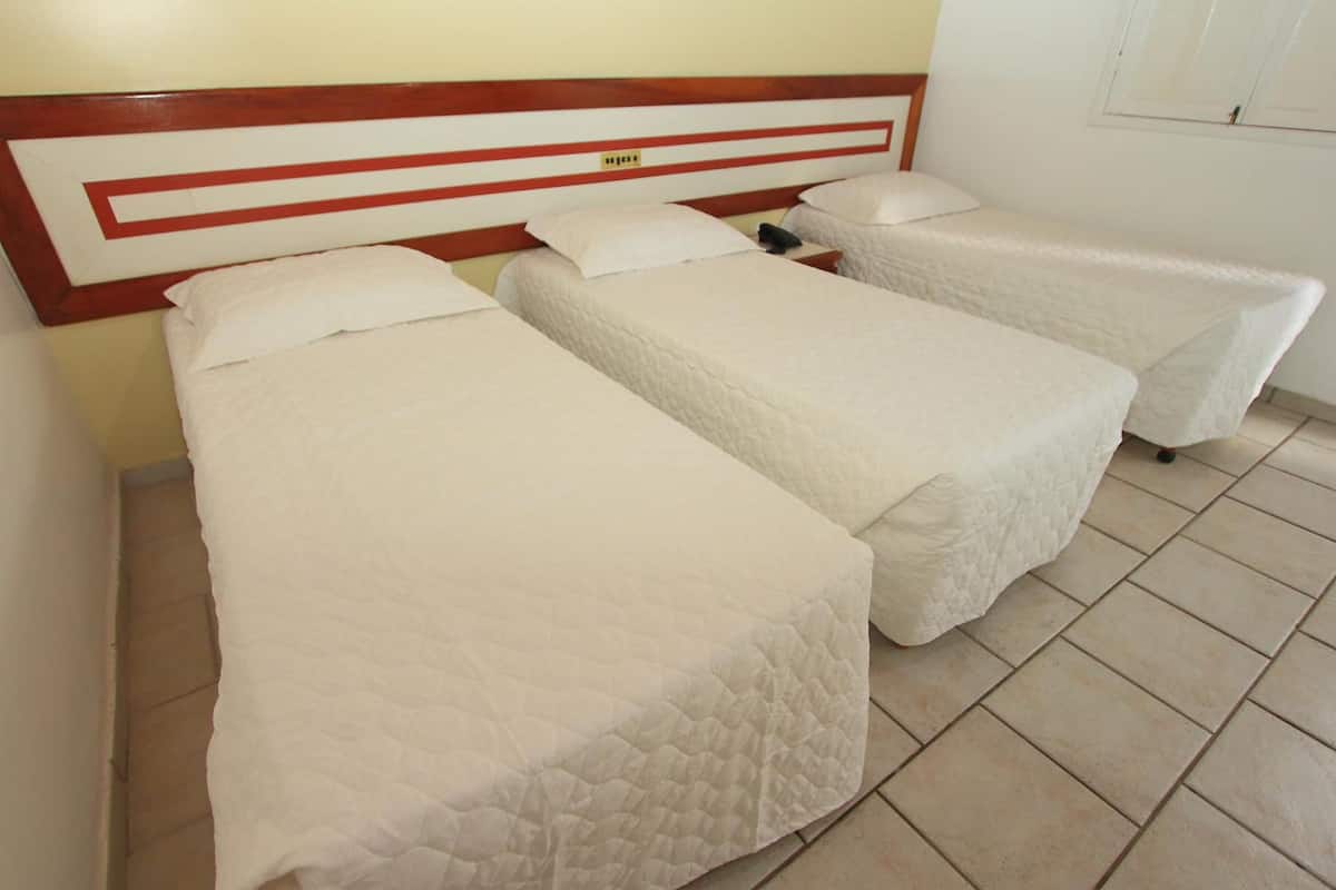 Una habitación con dos camas individuales, cada una con cabecero de madera y ropa de cama blanca.