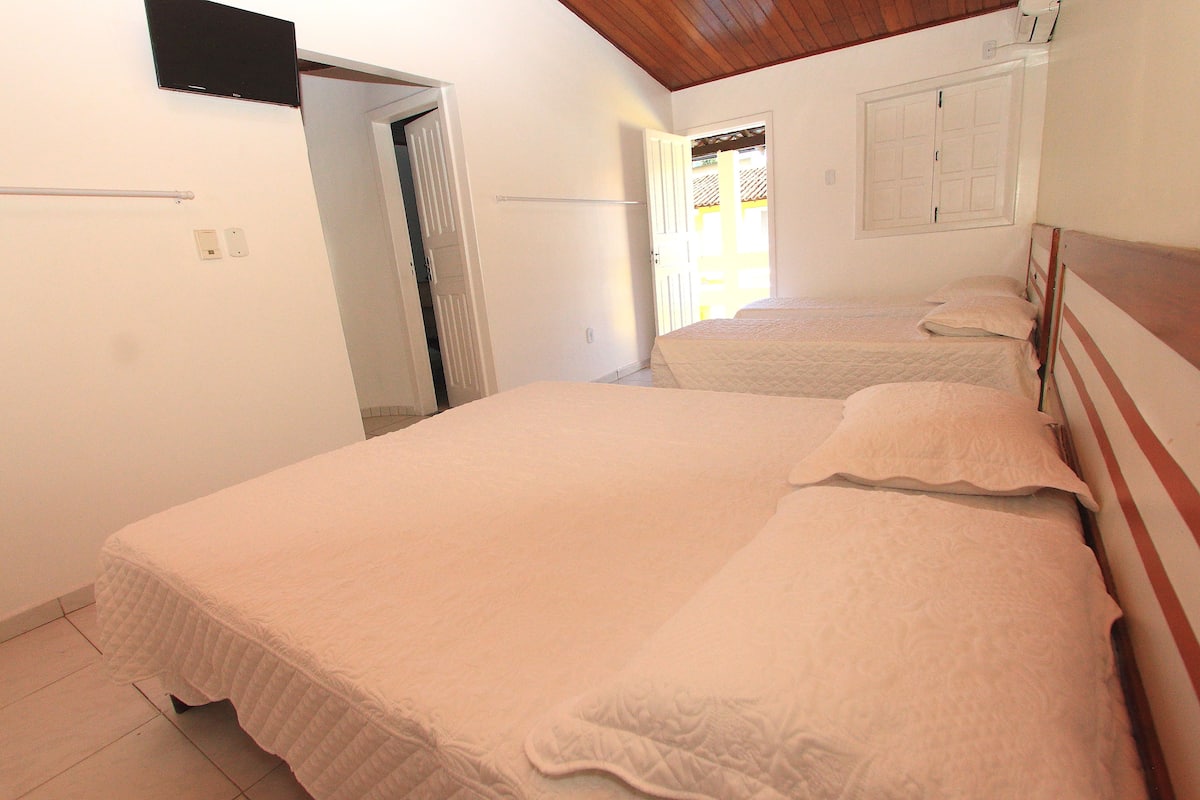 Un dormitorio con dos camas, techo de madera y puerta blanca.