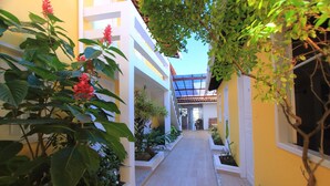 A narrow corridor with potted plants and a clear view of a building's interior. - Rede Andrade Porto Seguro Navegantes (Porto Seguro)