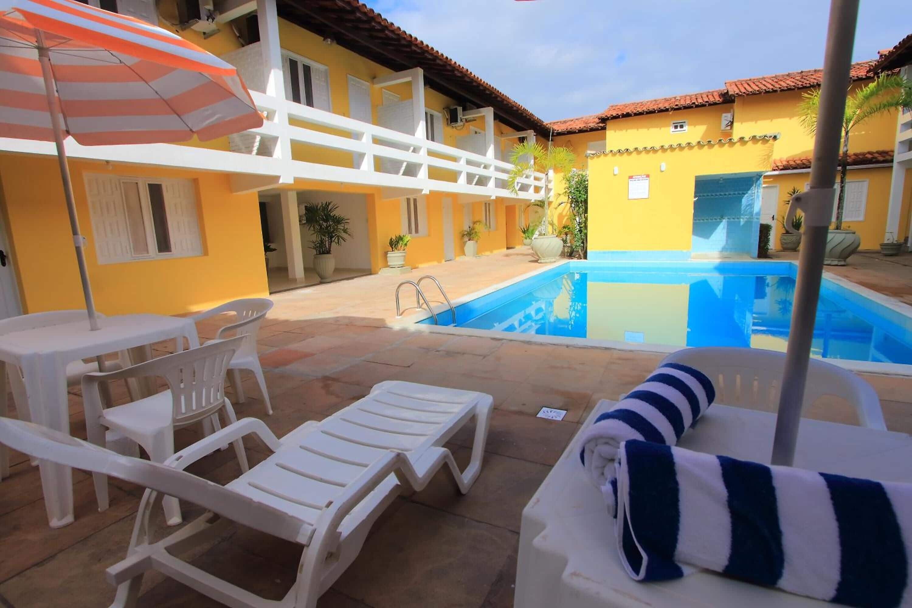 A poolside area with lounge chairs, a table, and an umbrella.