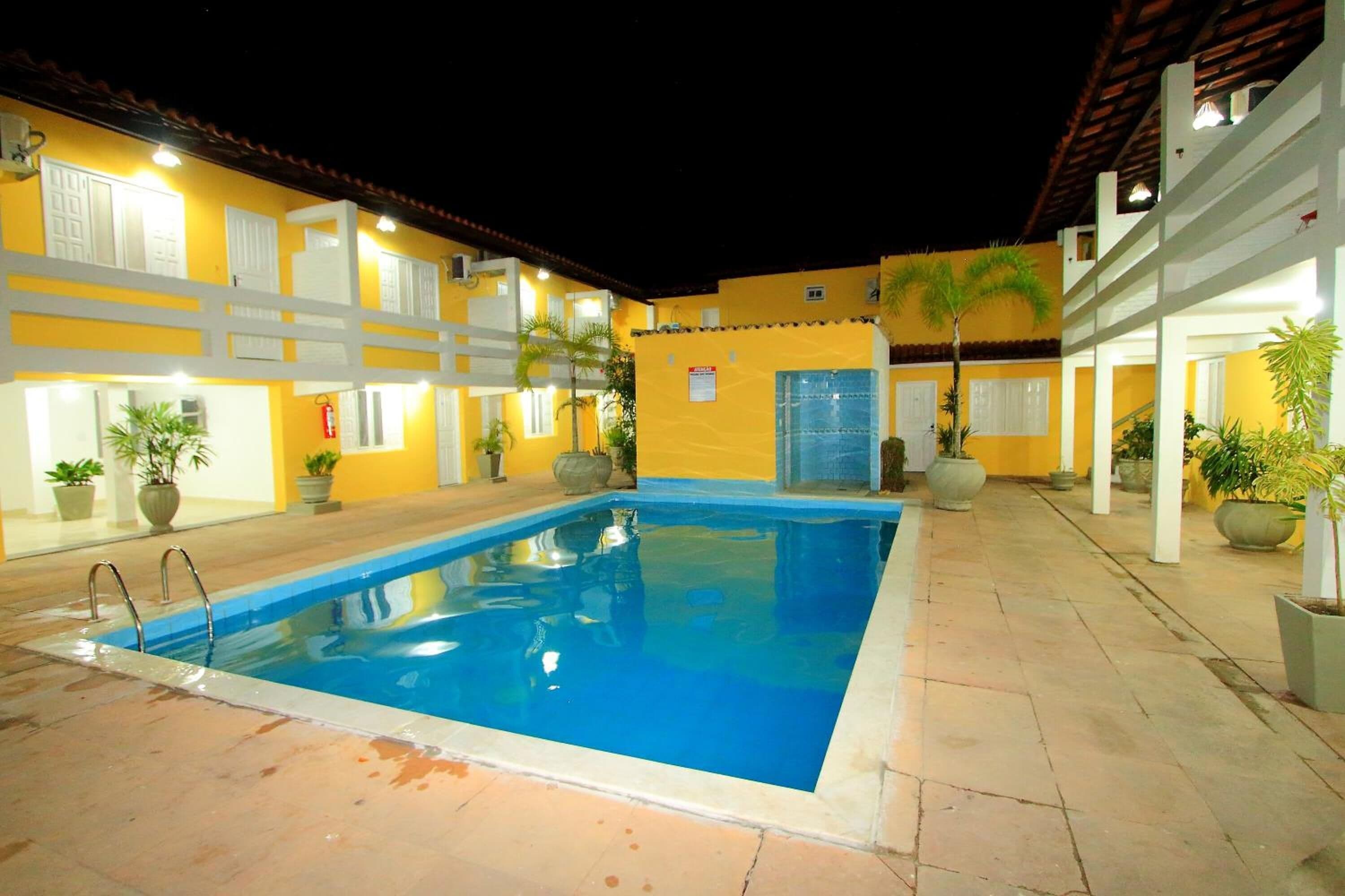 A swimming pool with a tiled deck, surrounded by yellow walls and white railings.