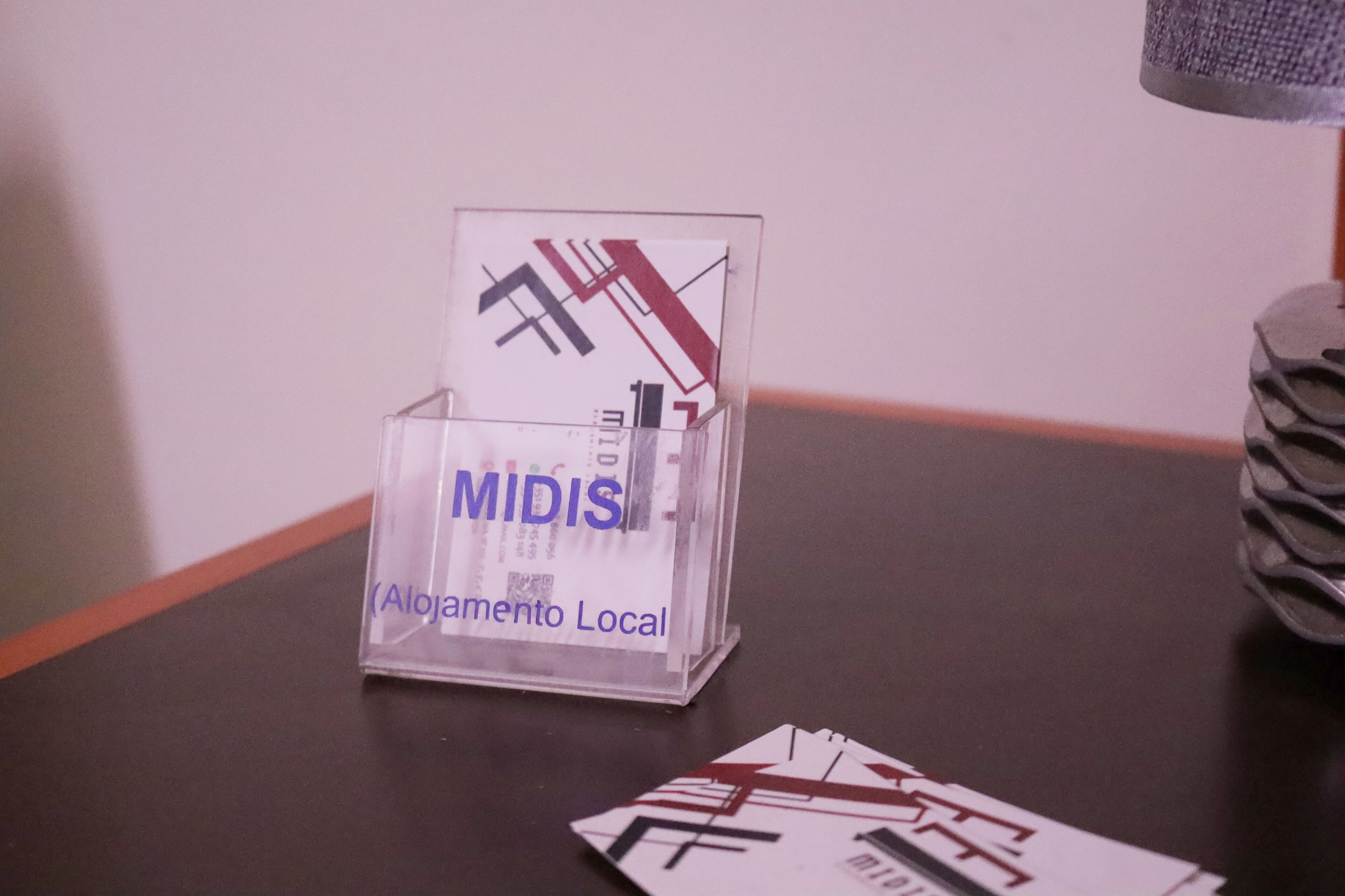Un présentoir en verre transparent, avec une plaque indiquant « MIDIS (hébergement local) », posé sur une surface sombre.