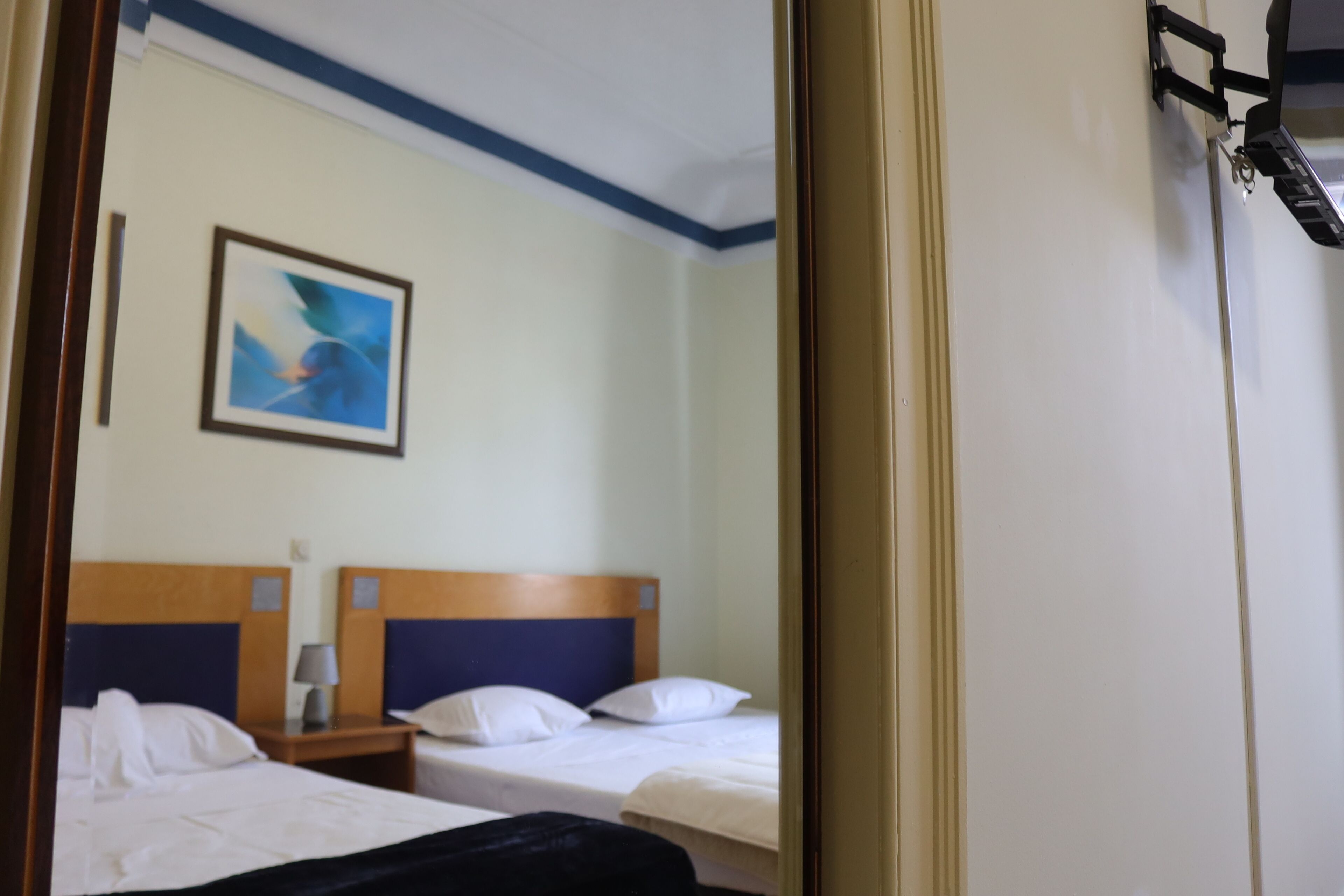 Et hotelværelse med to senge, et natbord, en lampe og et billede på væggen.