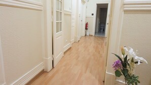 A hallway with wooden flooring, white walls, and doors leading to other rooms. - MIDIS - Local Accommodation (Lisbon)