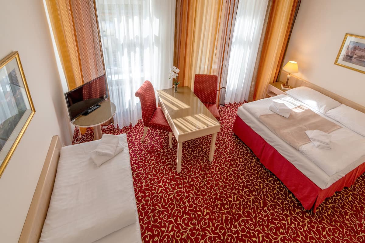 A hotel room with a bed, a desk, a chair, and a TV.
