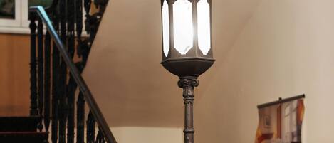 Una escalera con barandillas ornamentadas y una lámpara de pared de estilo antiguo.