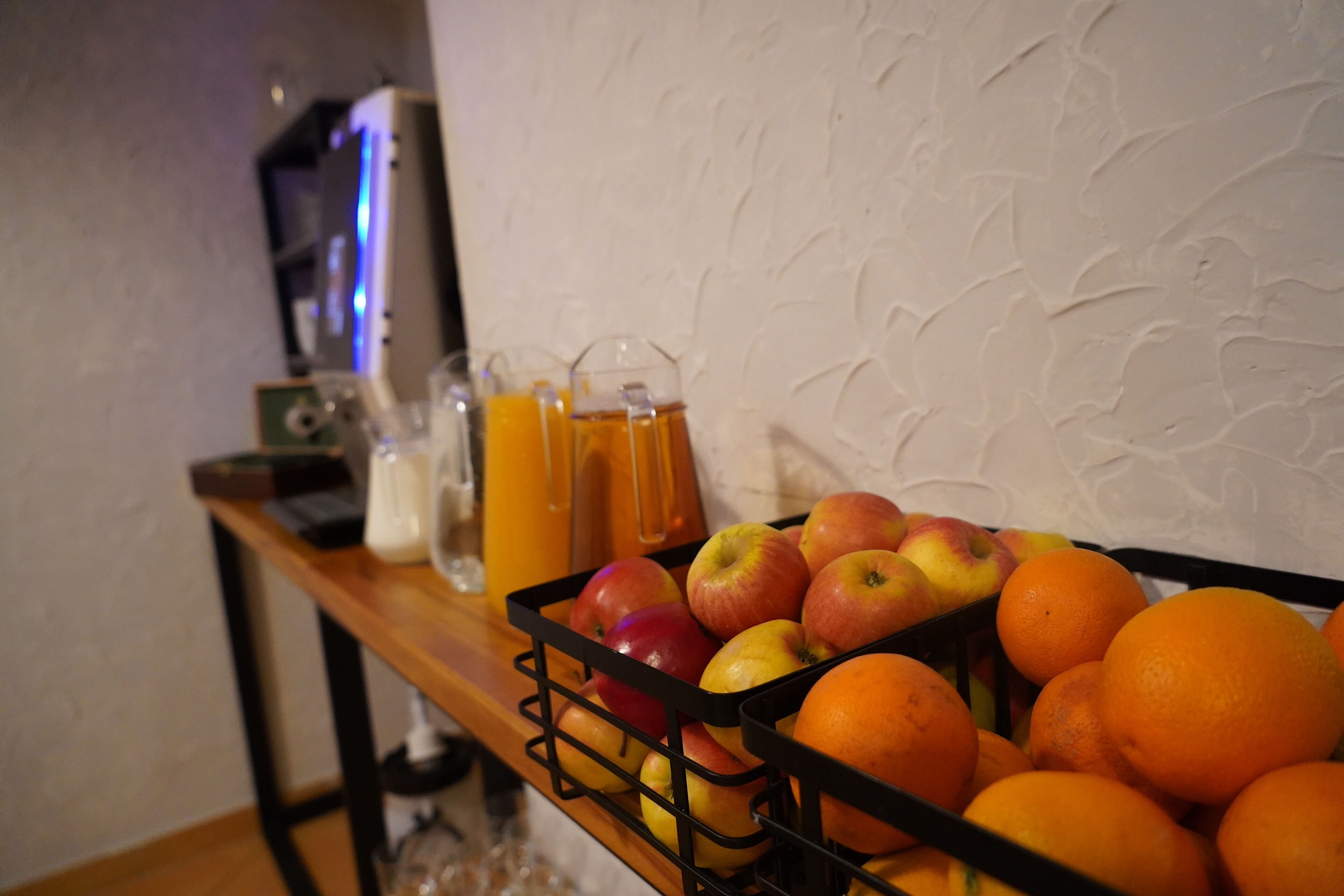 A fruit basket with apples and oranges on a wooden table.