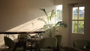 Una habitación con una mesa de comedor, sillas, una planta en maceta y un ventanal con vistas a la vegetación.