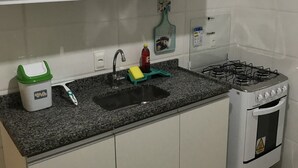 Eine Küche mit weißen Schränken, einer Granit Arbeitsplatte, einem Spülbecken, einem Gasherd und einem kleinen Backofen.