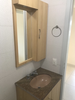 Un baño con un armario de madera, un espejo, un lavabo y un perchero para toallas.