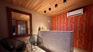Une cuisine moderne avec un plan de travail en marbre, deux chaises noires en fil de fer, une table ronde et un mur à motifs.