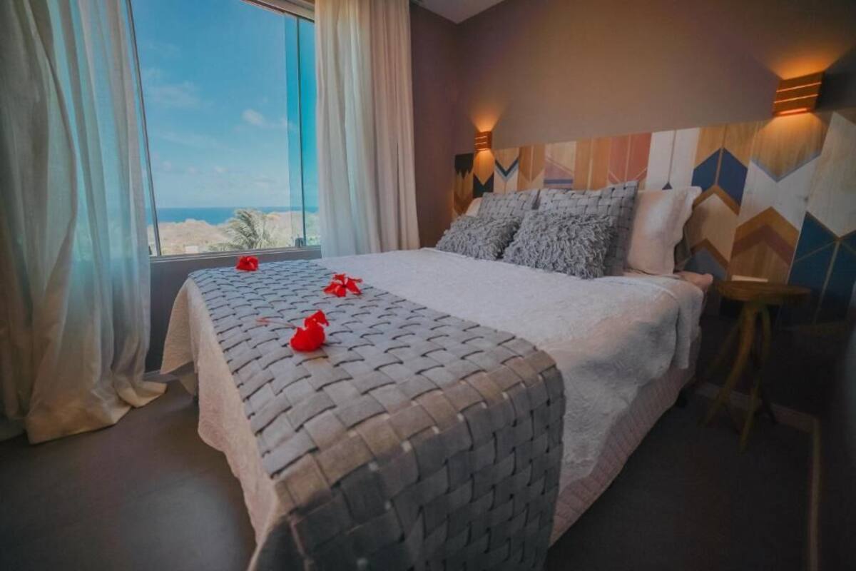Een slaapkamer met een groot bed, uitzicht op zee en een wand met een geometrisch patroon.