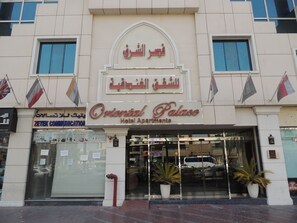 Entrada de un hotel con un letrero que dice 'Oriental Palace Hotel Apartments LLC' y banderas de varios países.