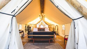 A tented room with a bed, a chandelier, and a rug. - Collective Hill Country Retreat (Wimberley)