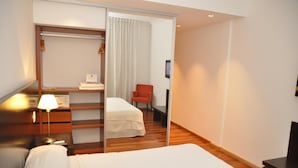 Una habitación de hotel con una cama, un escritorio, una silla y un armario.