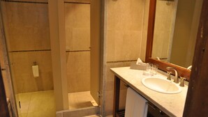 Un baño con ducha envuelta en vidrio, un lavabo con espejo y un perchero para toallas.