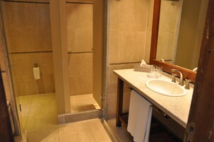 Un baño con ducha envuelta en vidrio, un lavabo con espejo y un perchero para toallas.