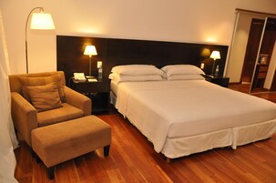 Una habitación de hotel con una cama grande, una silla, una mesita de noche y una lámpara.