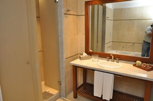 Un baño con un espejo grande, un lavamanos y una ducha.