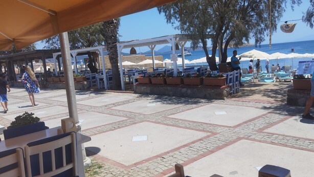 En utomhusplats med bord och stolar, en pergola och utsikt över havet.