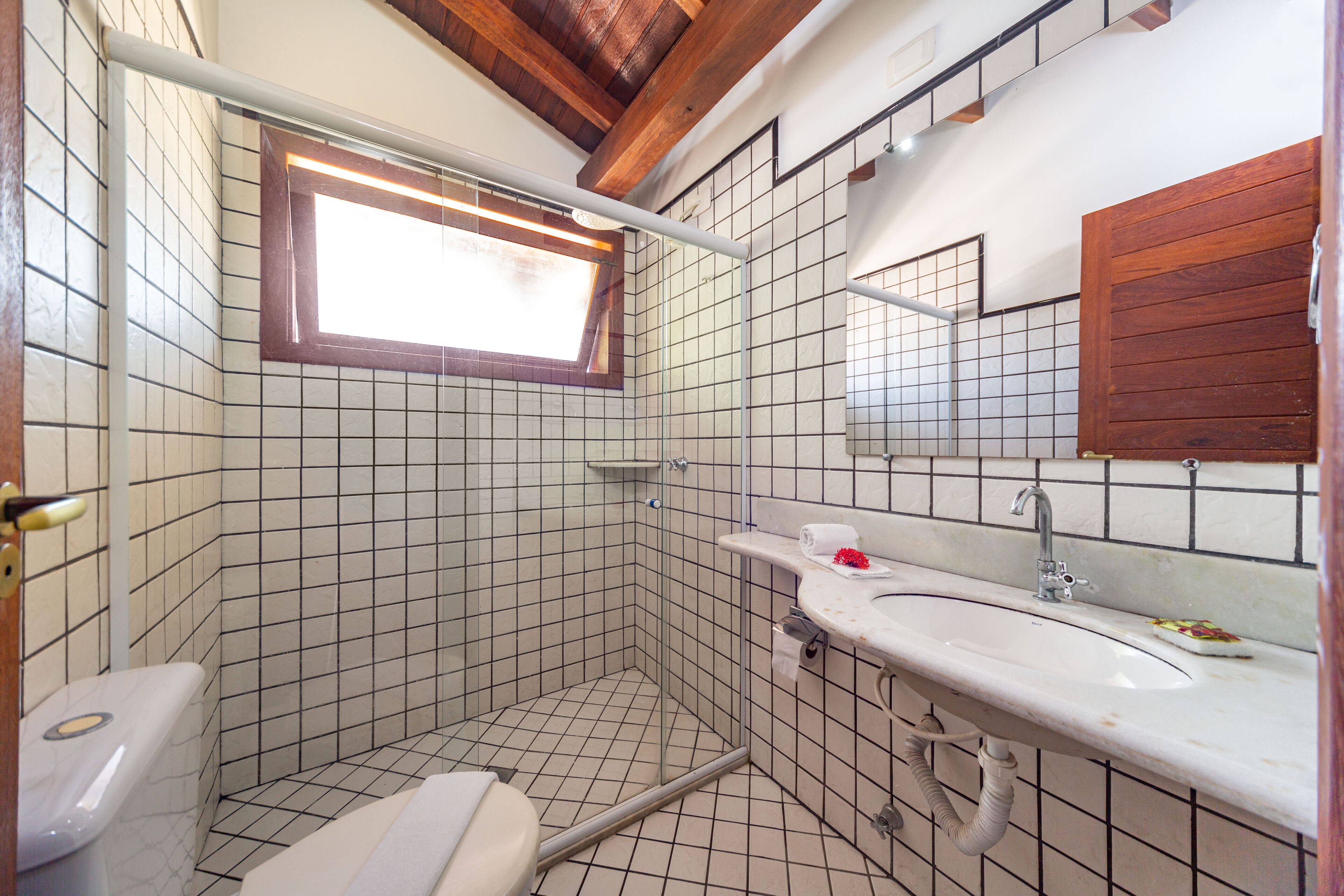 Ein Badezimmer mit Dusche, Toilette, Waschbecken und einem Fenster.