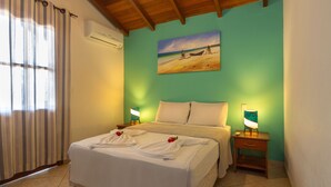 Une chambre d’hôtel avec un lit, un tableau représentant une scène de plage et une table de chevet avec une lampe.