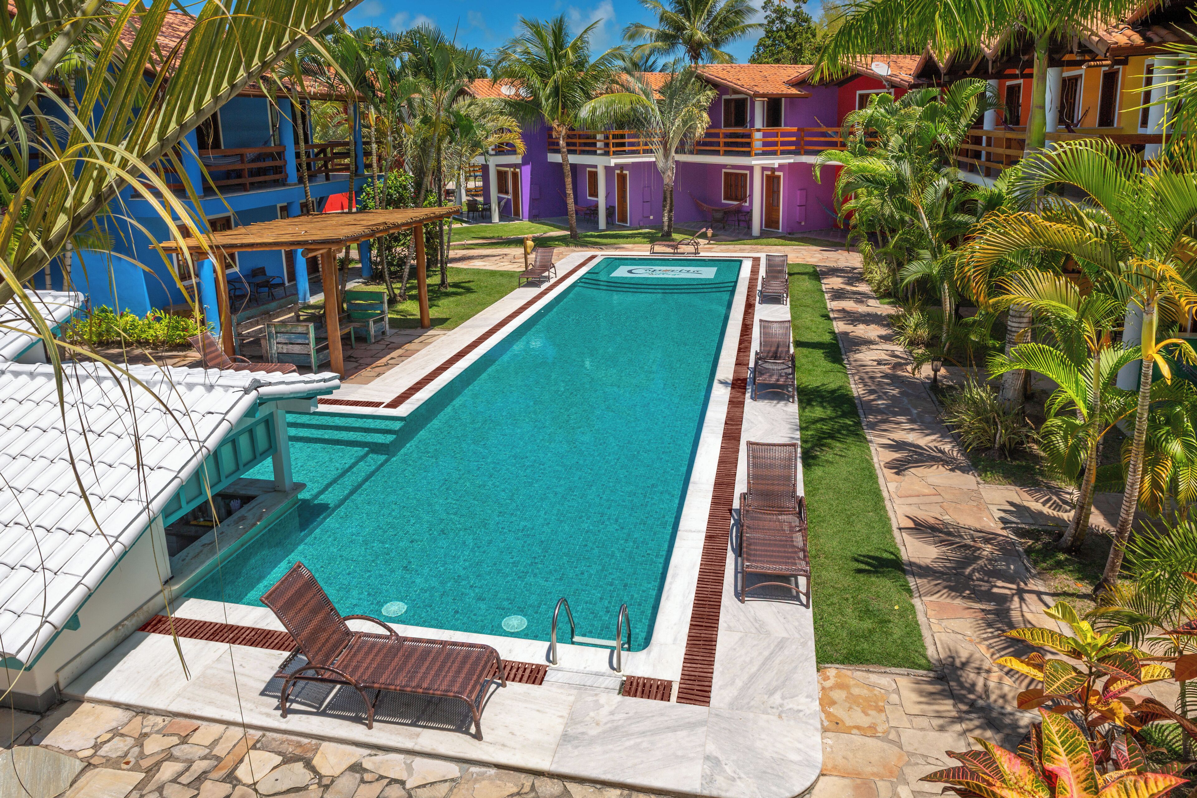 Ein Swimmingpool mit Liegestühlen, einer überdachten Lounge und einem Gebäude mit rotem Dach.