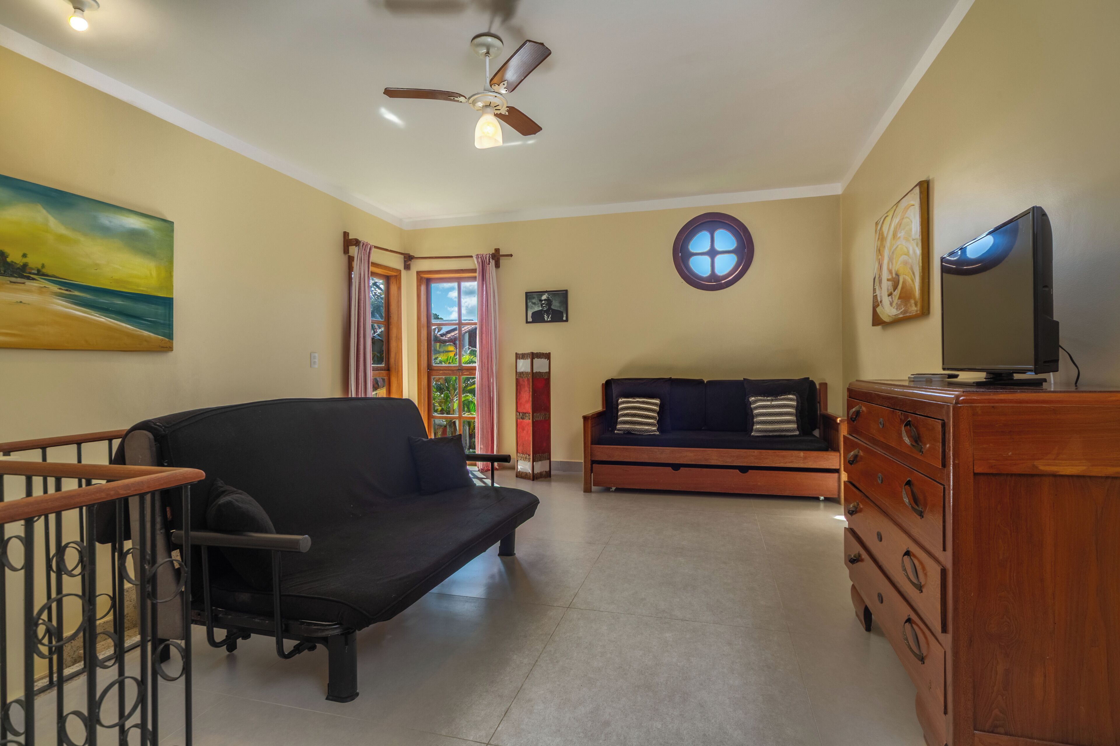 A living room with a ceiling fan, a sofa, a TV, and a wooden dresser.