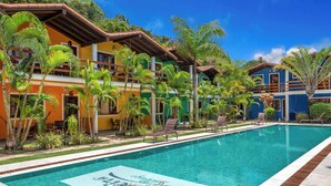 A swimming pool with a tiled design, surrounded by palm trees and buildings with balconies.