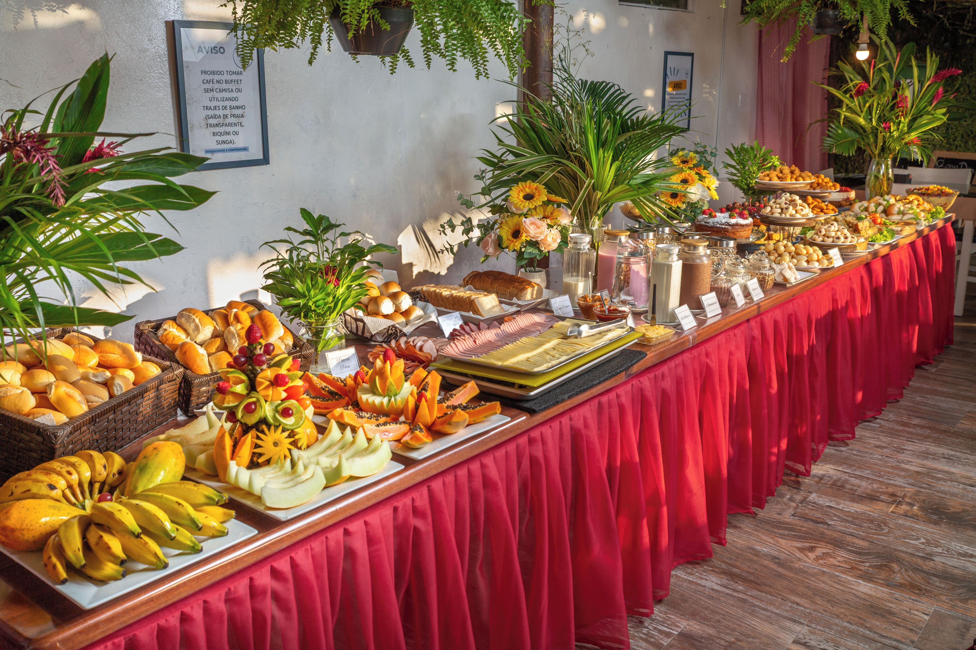 A buffet table with various food items and a red tablecloth.