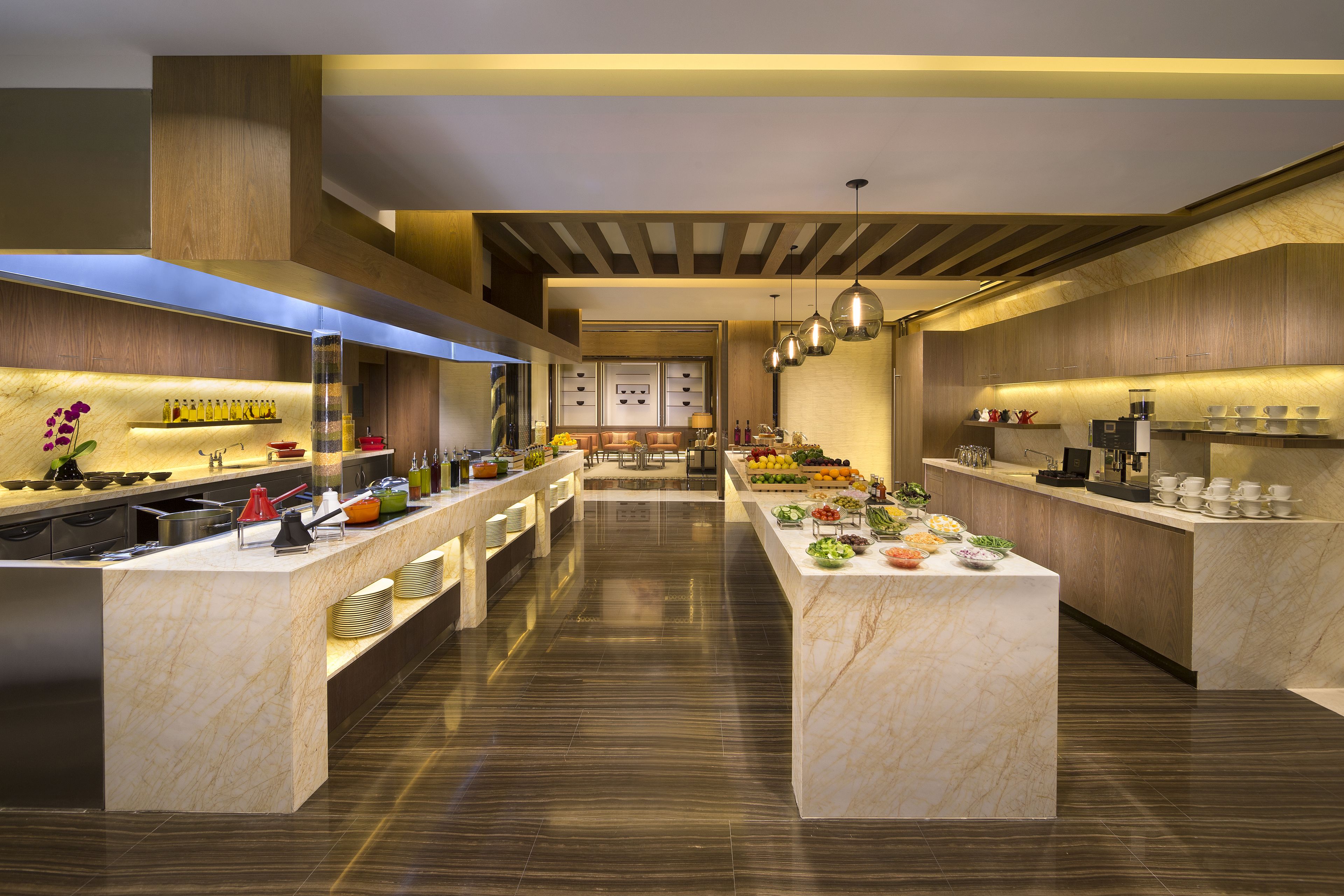 Une cuisine moderne dotée de plans de travail en marbre, d’éléments décoratifs en bois et de luminaires suspendus.