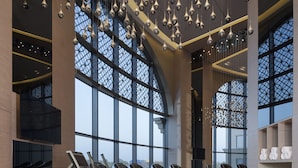 Une salle de sport moderne équipée de tapis de course, de vélos elliptiques et dotée d’un grand espace ouvert avec de hauts plafonds et des luminaires suspendus.