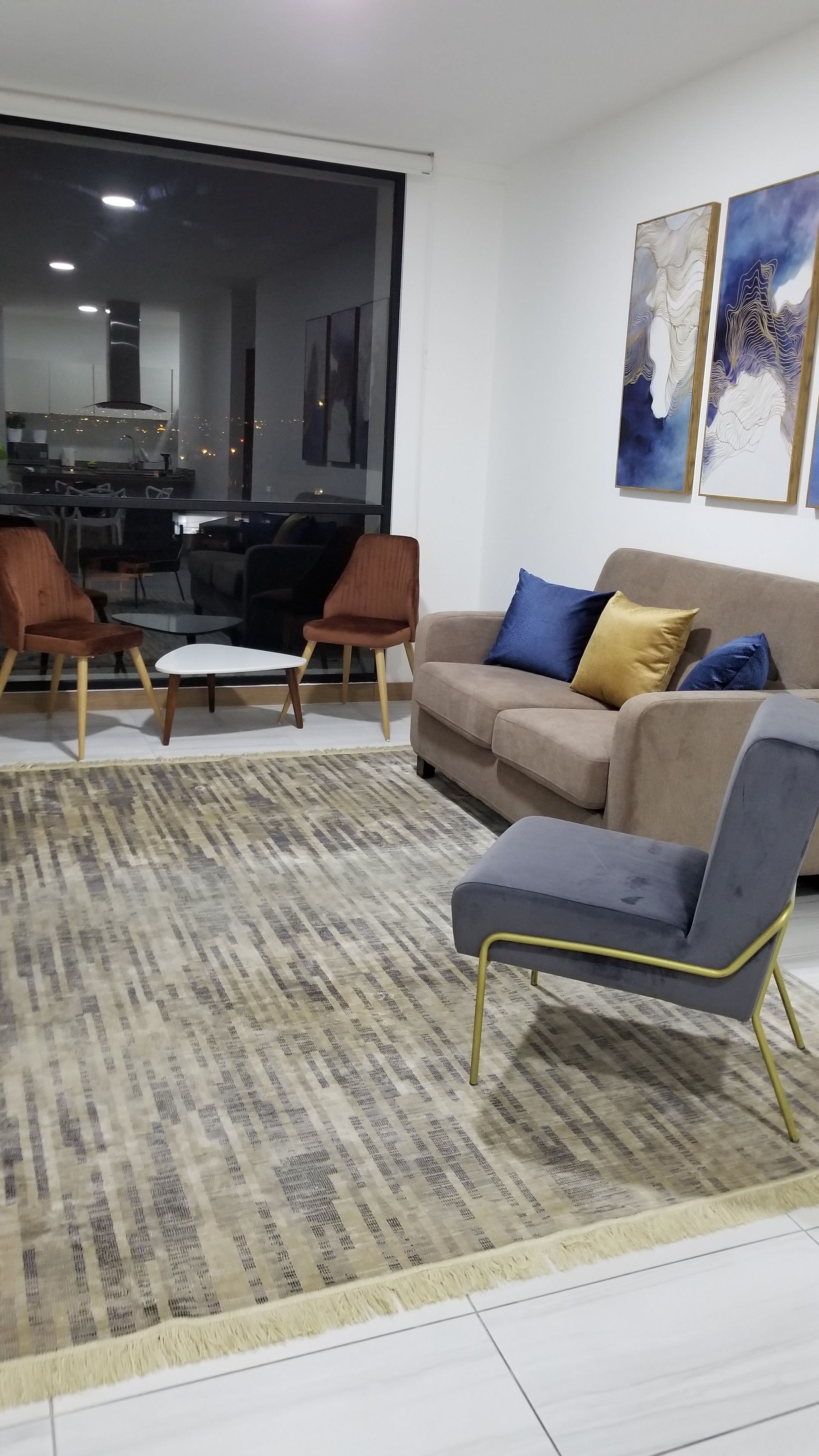 A modern living room with a sofa, two armchairs, a coffee table, and a patterned rug.