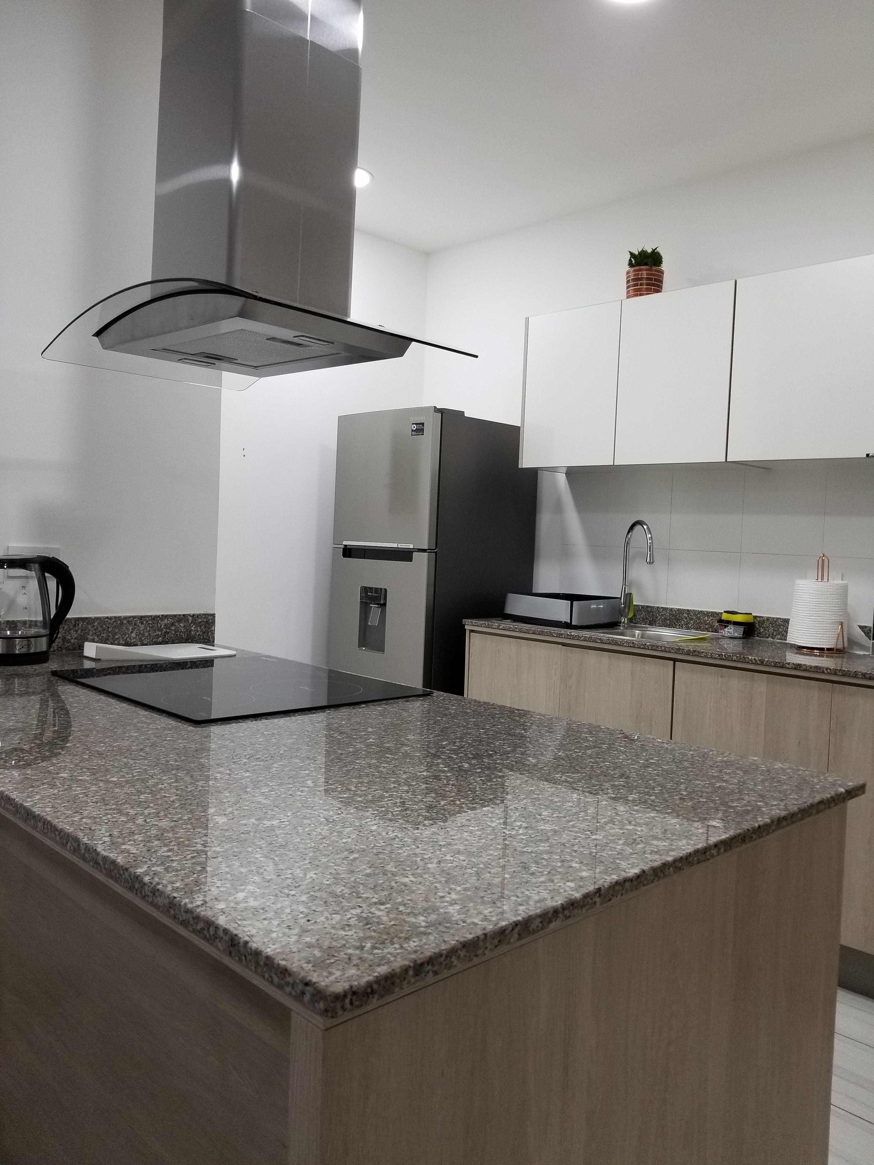 Eine moderne Küche mit Granit Arbeitsplatten, Edelstahlgeräten und weißen Schränken.