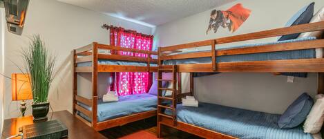 A bunk bed room with a desk, a lamp, and a plant.