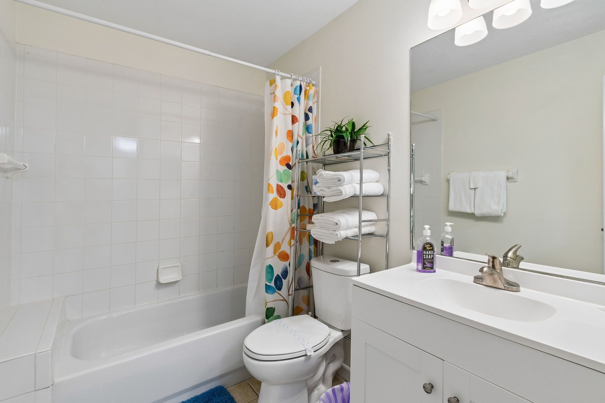 A bathroom with a bathtub, toilet, and a shelf with towels and toiletries.