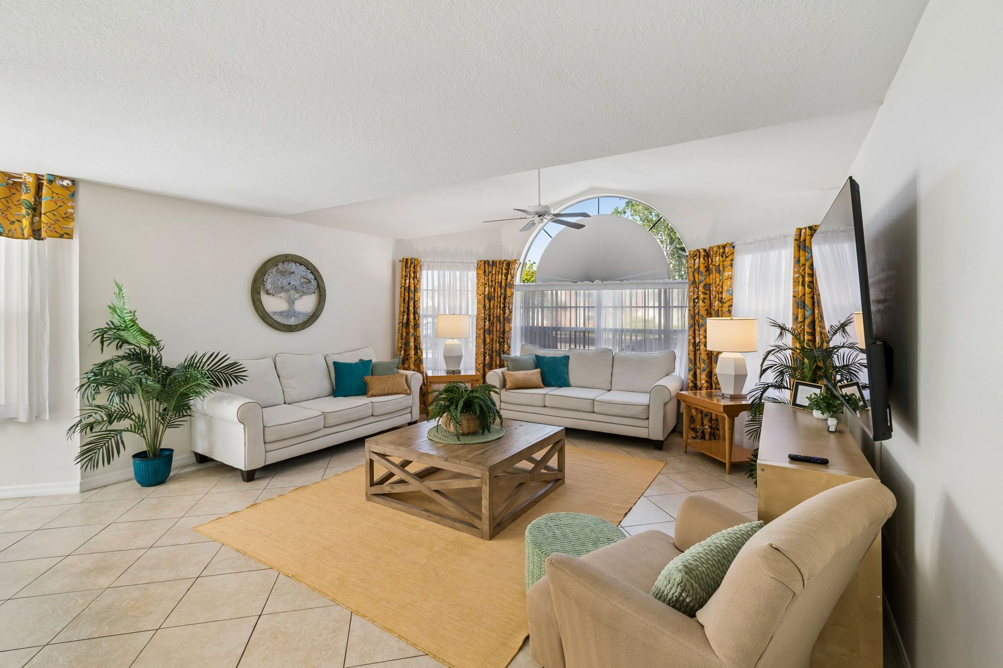 A living room with a sofa set, a coffee table, a TV, and a ceiling fan.