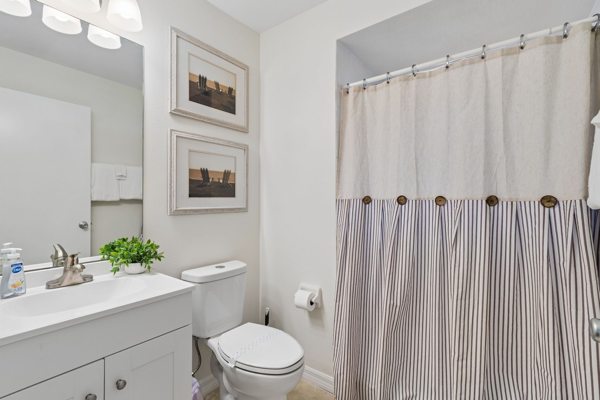 A bathroom with a white sink, toilet, and shower curtain.