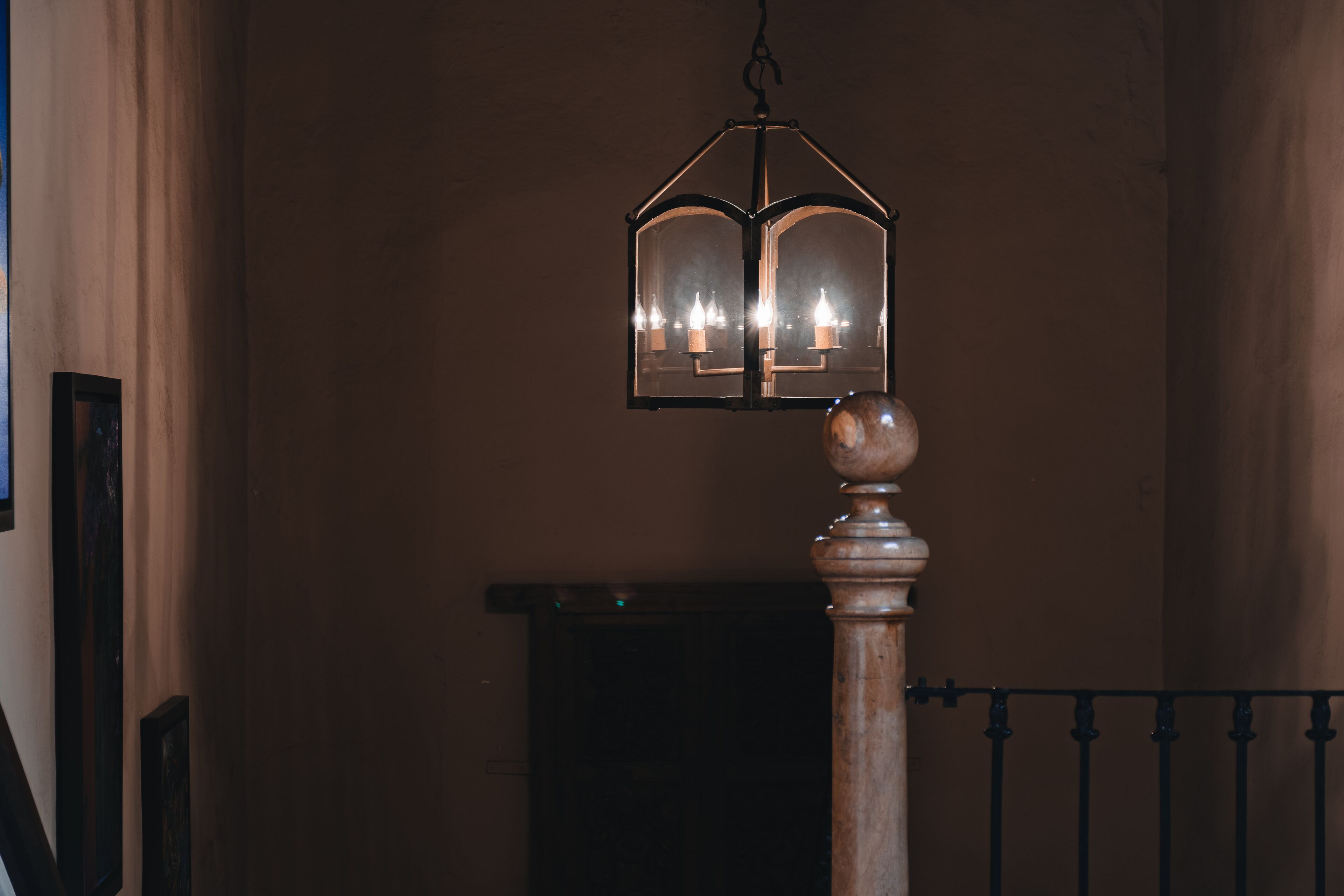 A staircase with a wooden balustrade and a hanging lantern with multiple candles.