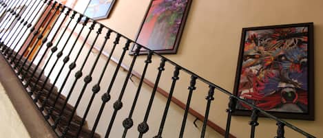 A staircase with ornate metal railings and framed artwork on the walls.