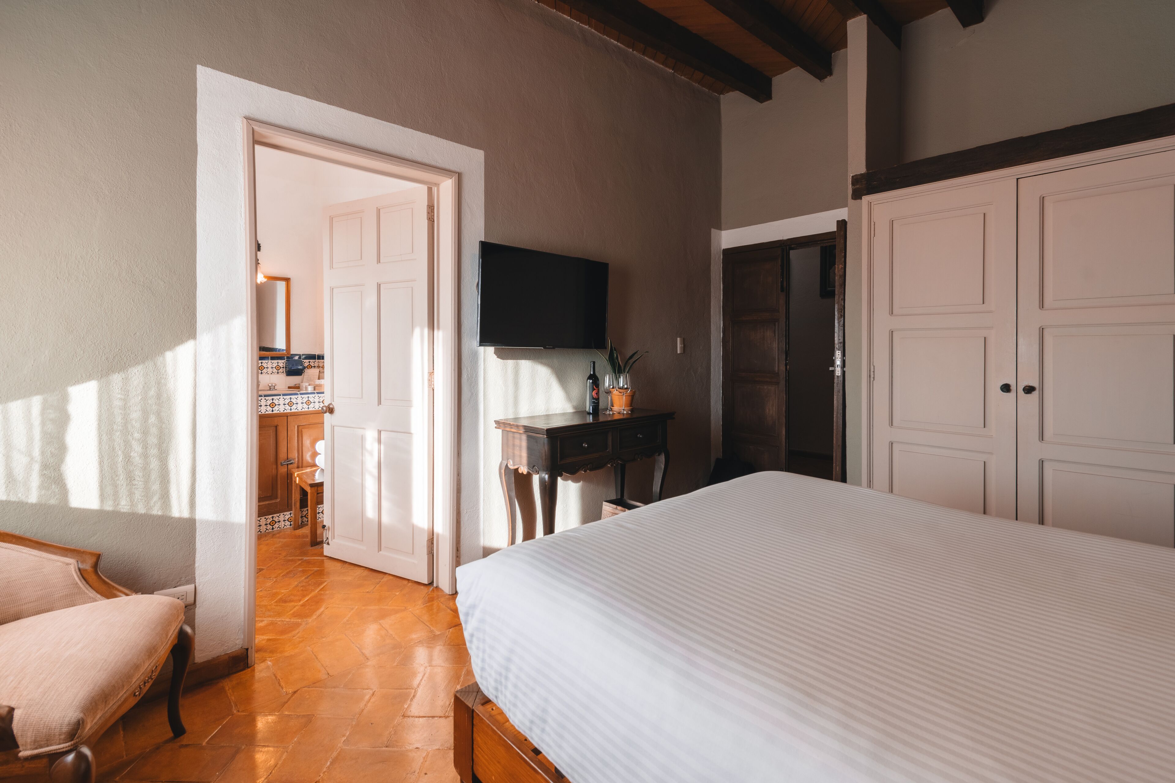 A bedroom with a bed, a desk, a TV, and a wardrobe.
