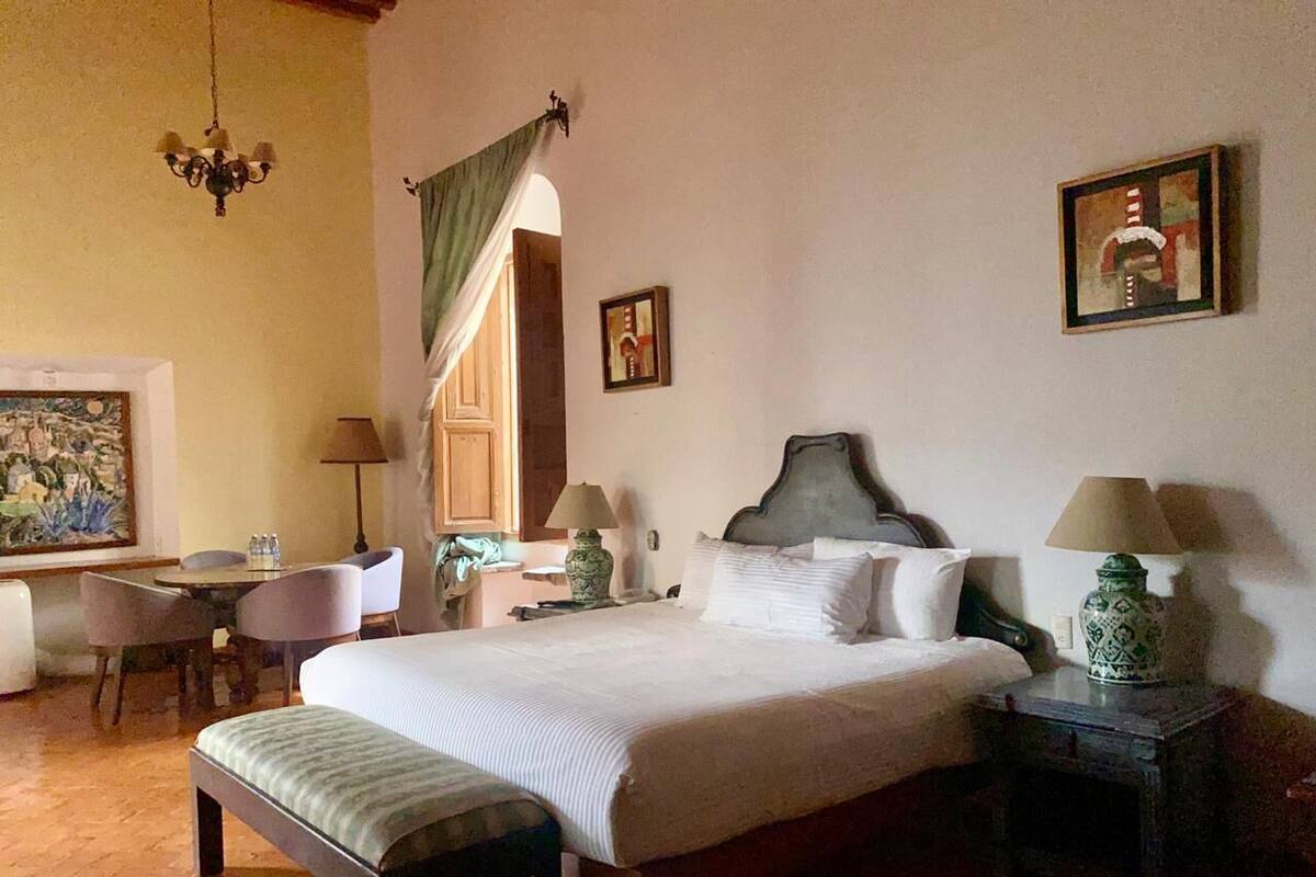Habitación de hotel con una cama grande, un escritorio, una silla y dos mesitas de noche con lámparas.