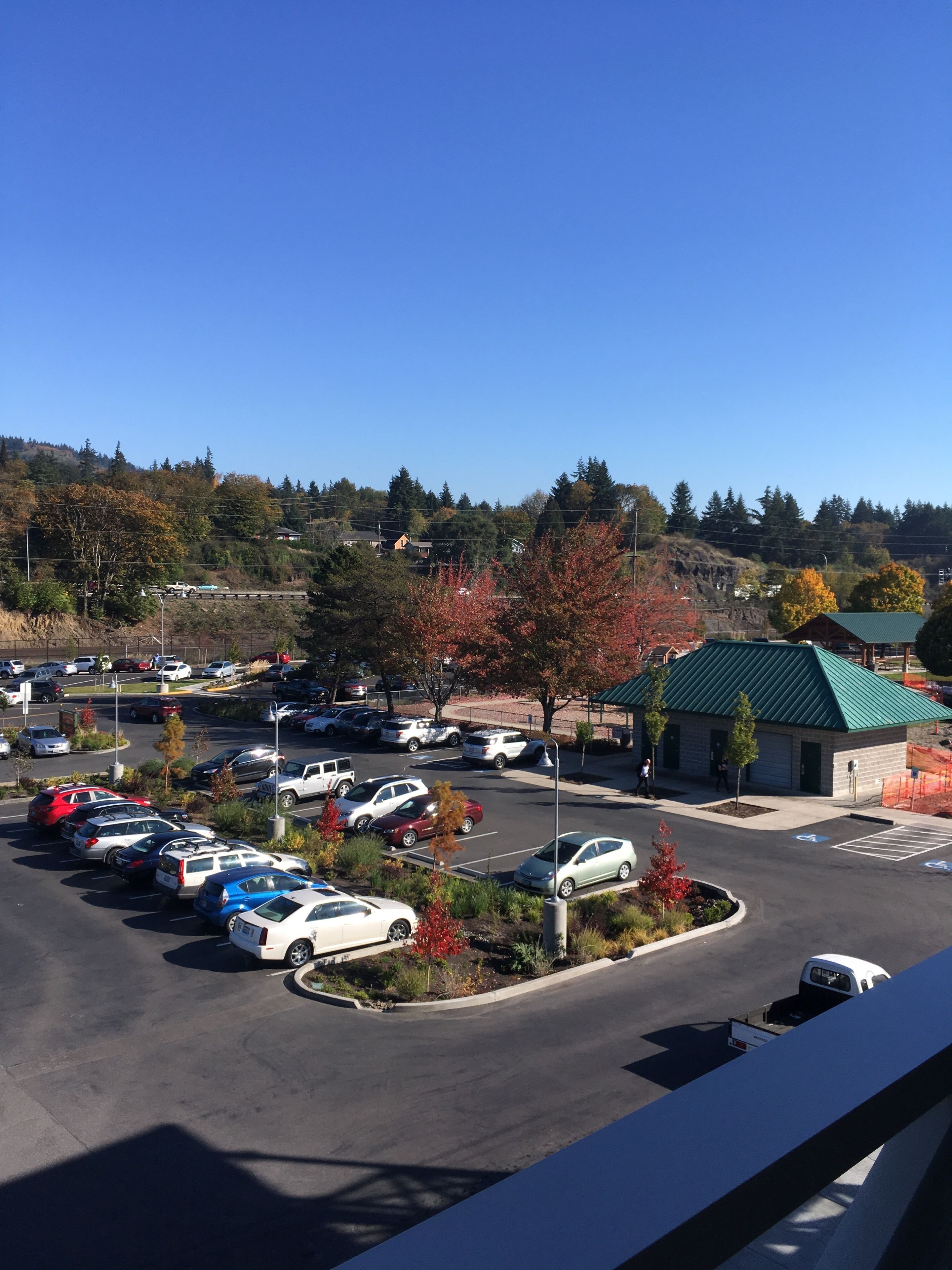 Un parking rempli de voitures, un bâtiment doté d’un toit végétalisé et des arbres aux feuilles d’automne.