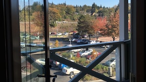 A view from a room with a glass door, overlooking a parking area with cars and autumn trees.