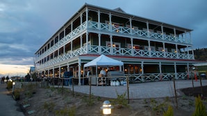 A multi-story building with a balcony, a covered outdoor area, and a paved walkway.