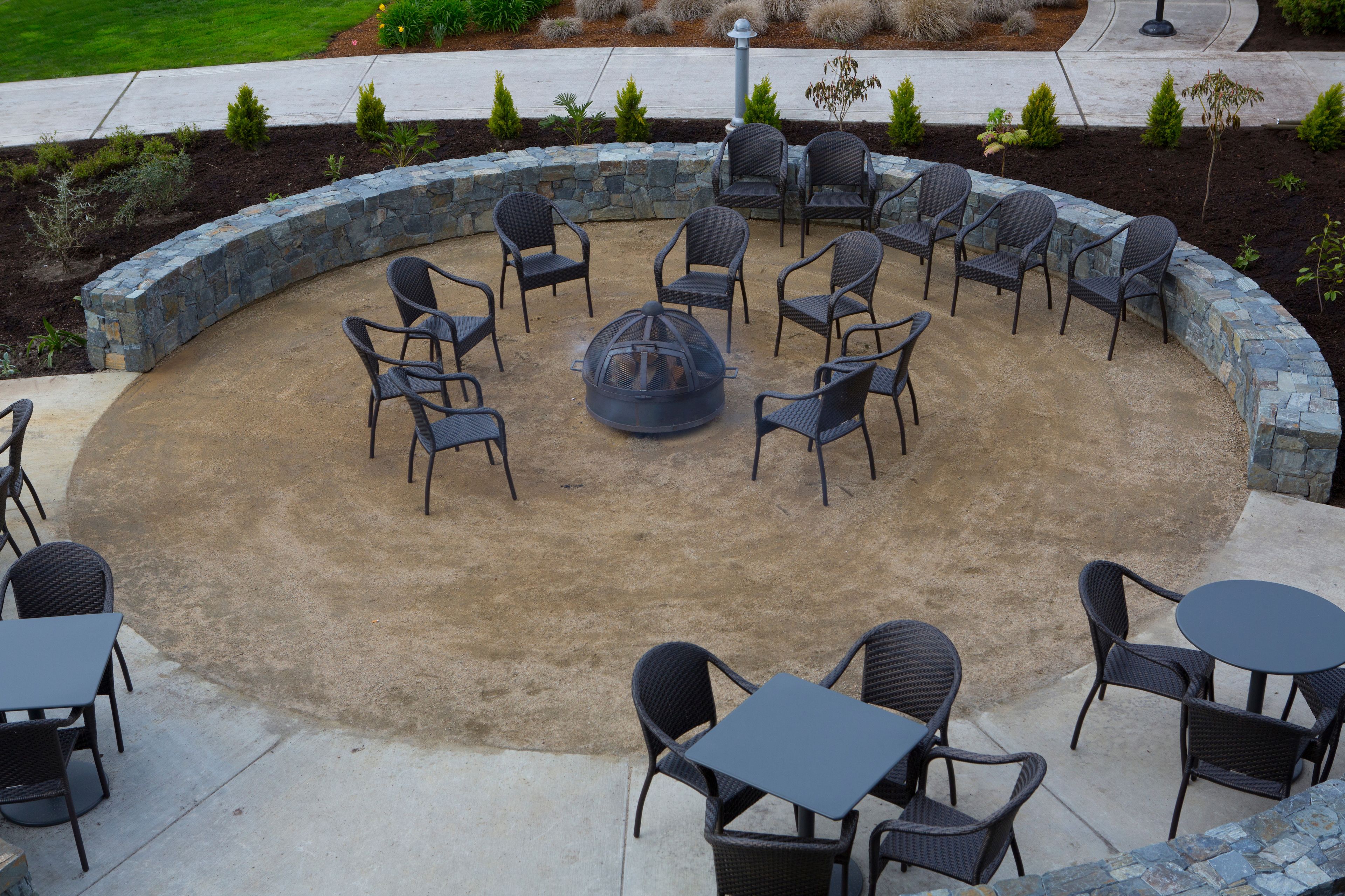 A circular outdoor seating area with stone walls, surrounded by chairs and tables.