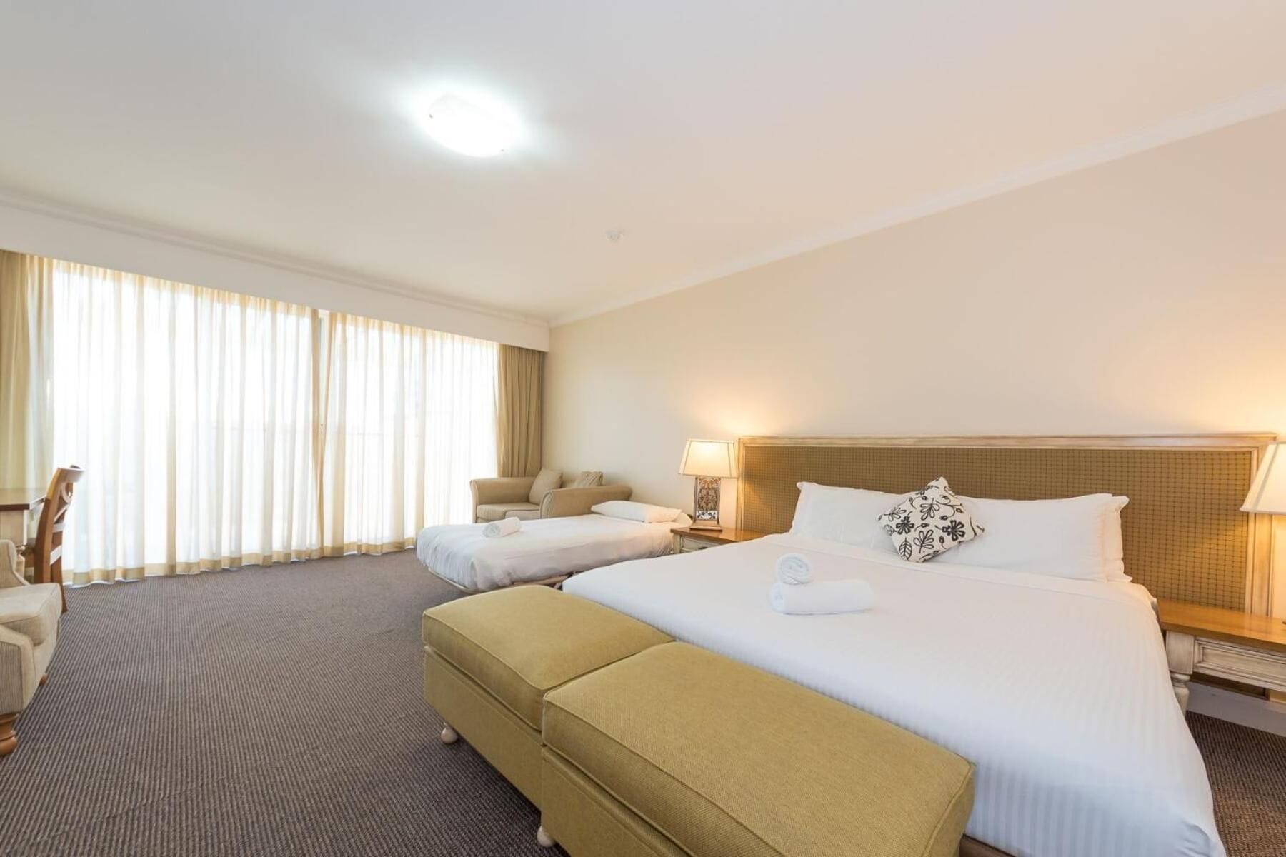 Une chambre d’hôtel avec un grand lit, un lit plus petit, un canapé et un fauteuil.