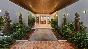 A hallway with a wooden ceiling, stone statues, and potted plants. - Harrington River Lodge (Harrington)
